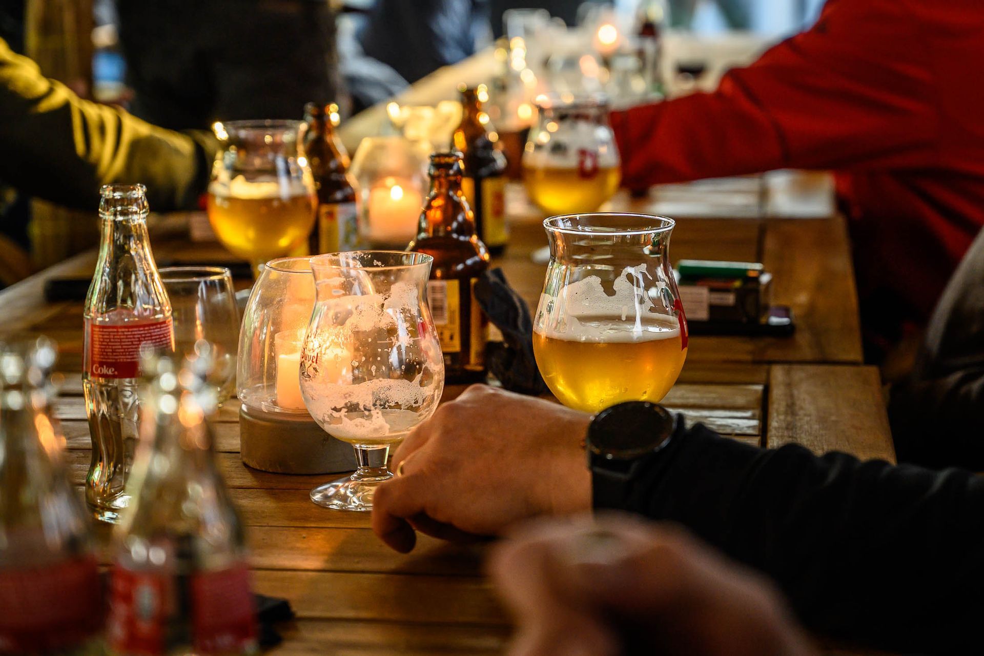 Een groep mensen zit aan een tafel met glazen bier en flessen bier.