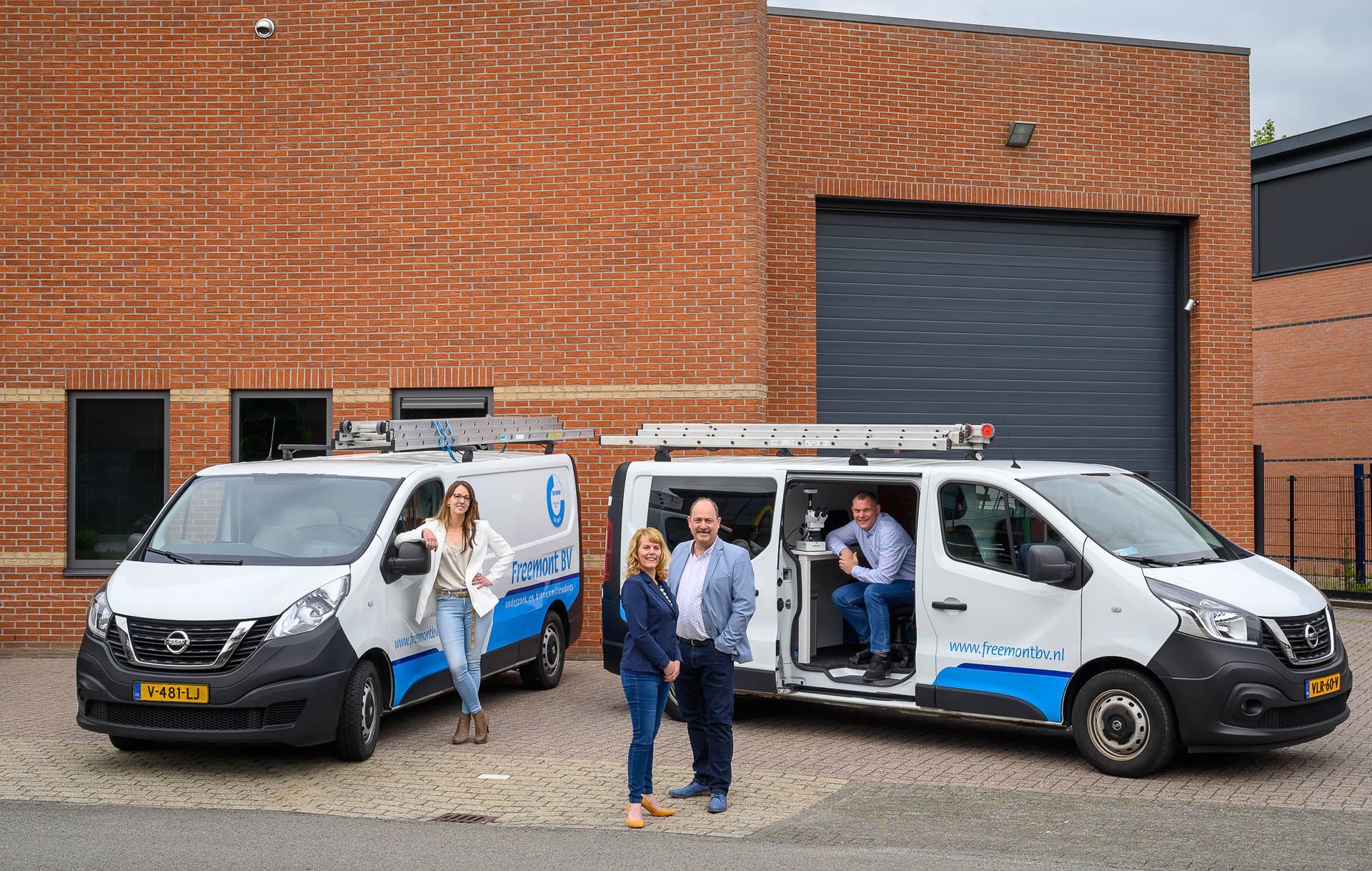 Drie busjes staan geparkeerd voor een stenen gebouw.