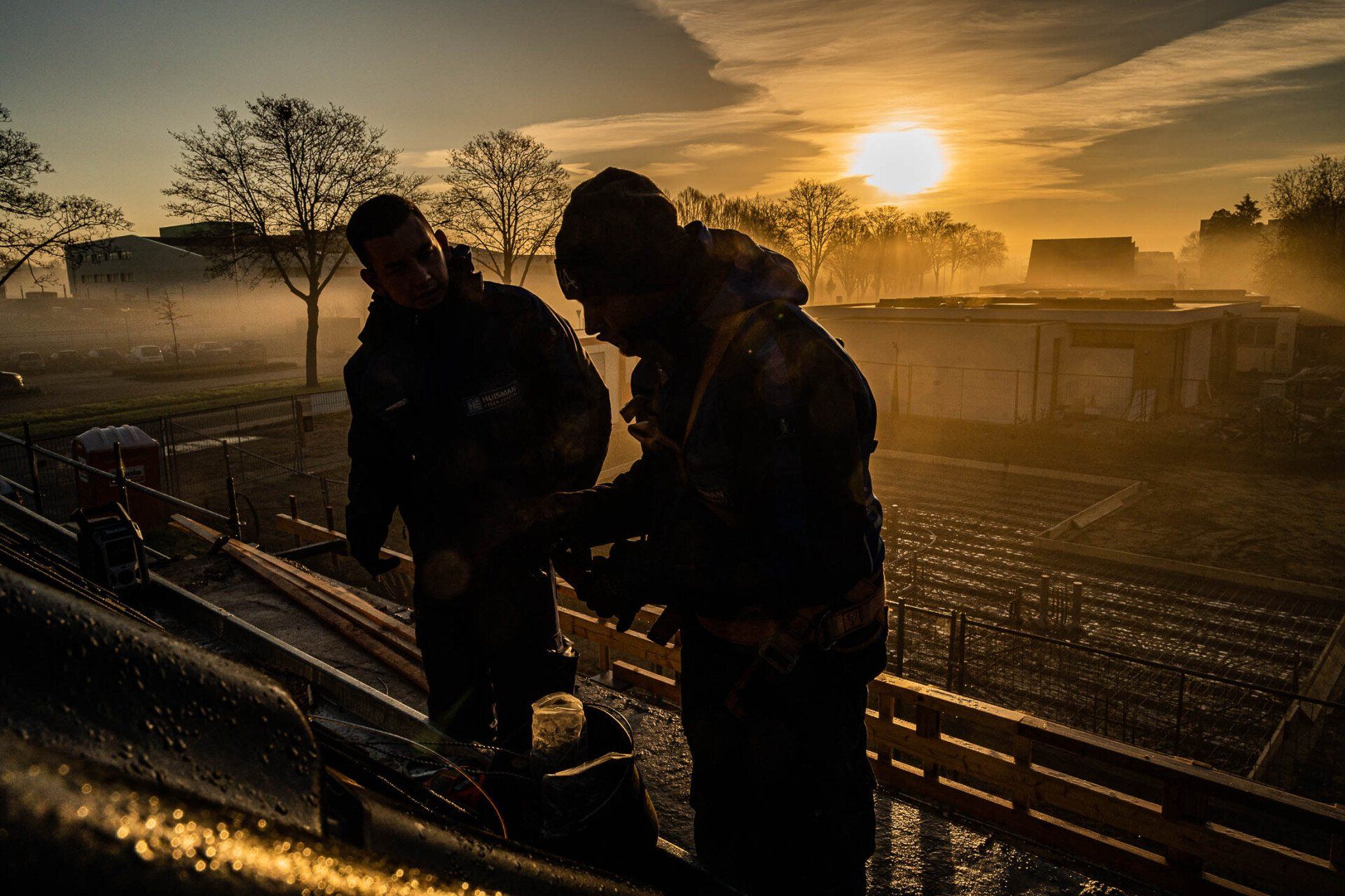 Twee mannen werken op een bouwplaats bij zonsopgang.