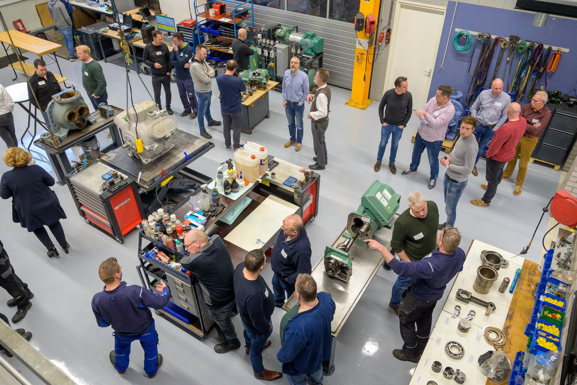 Een groep mensen staat rond een machine in een fabriek.