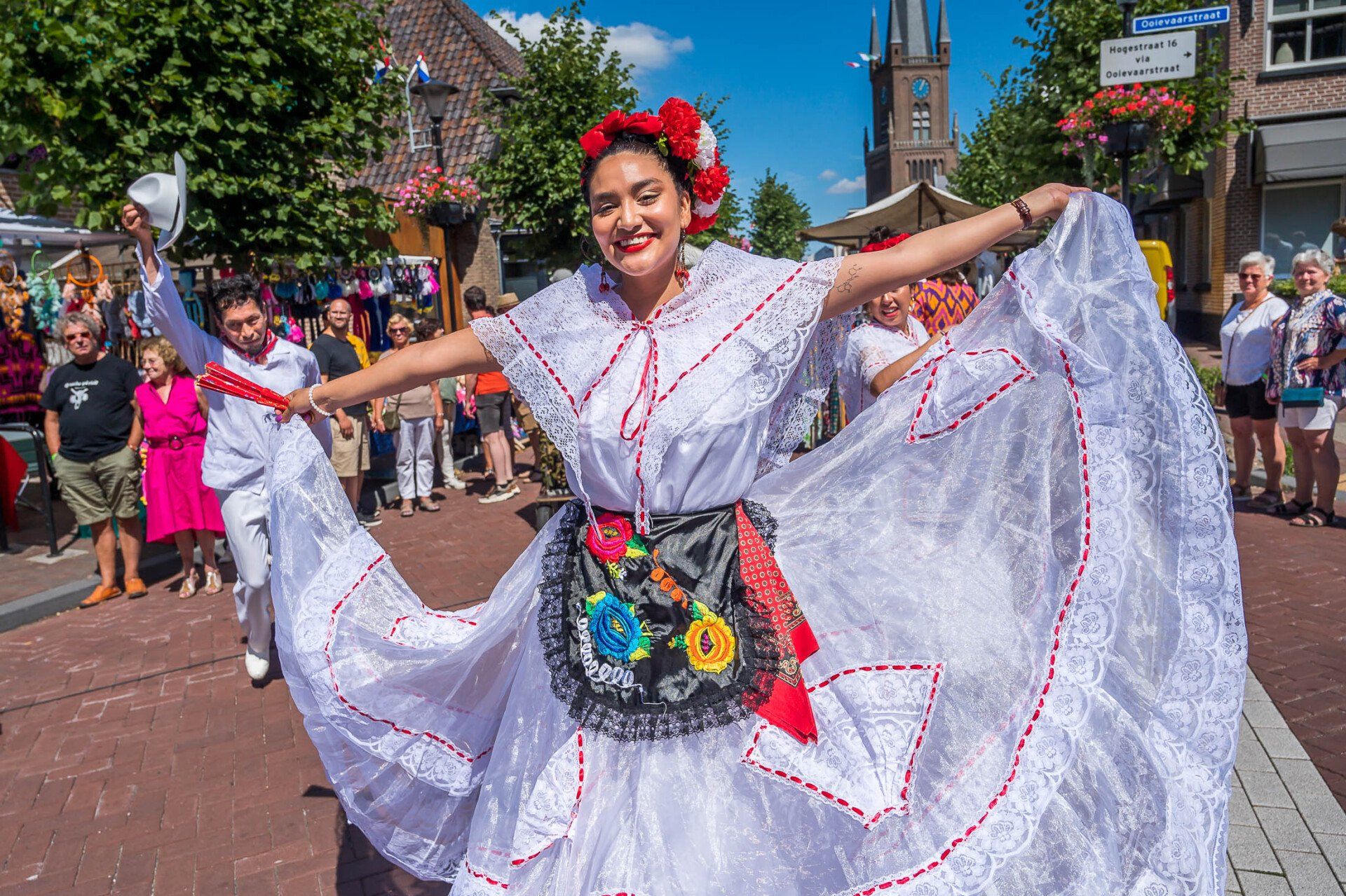 Een vrouw in een witte jurk danst voor een menigte.