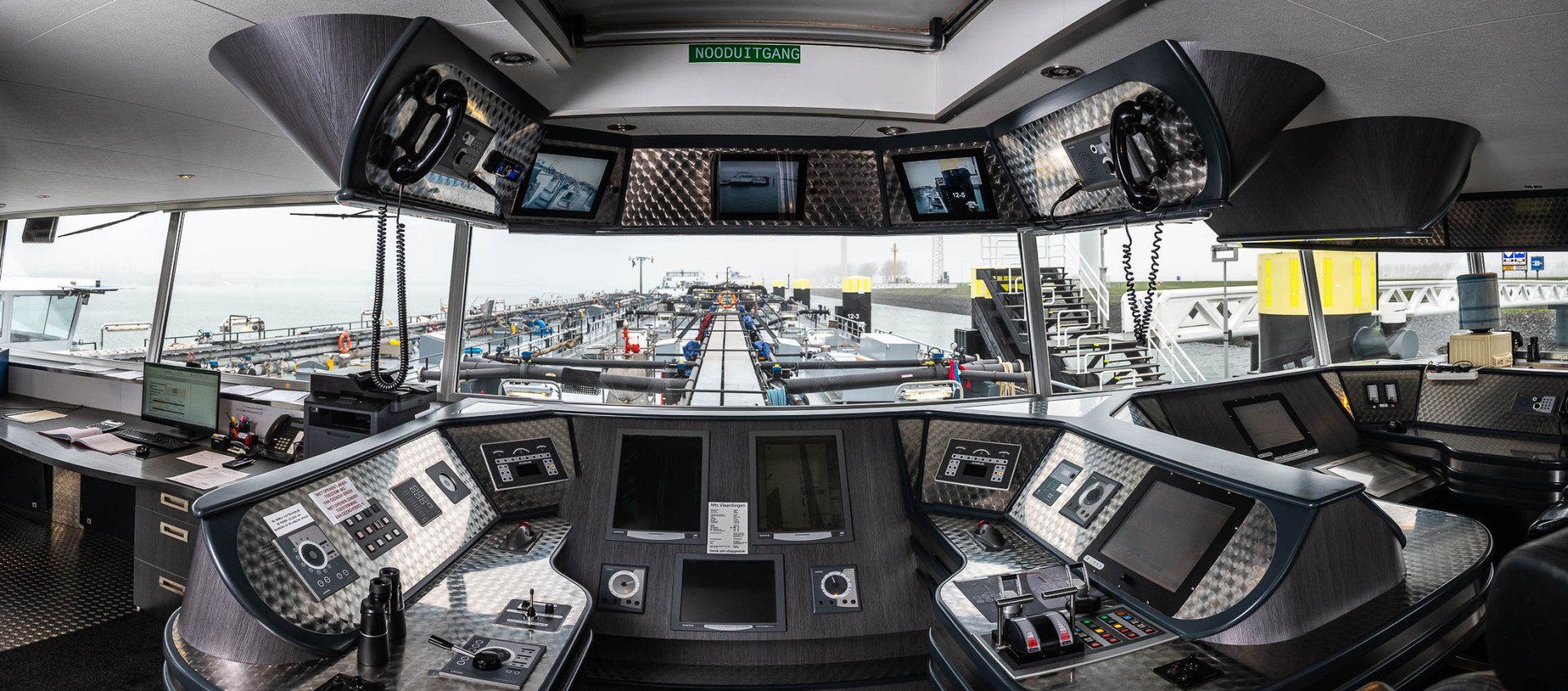 De cockpit van een boot met veel monitoren en bedieningselementen.
