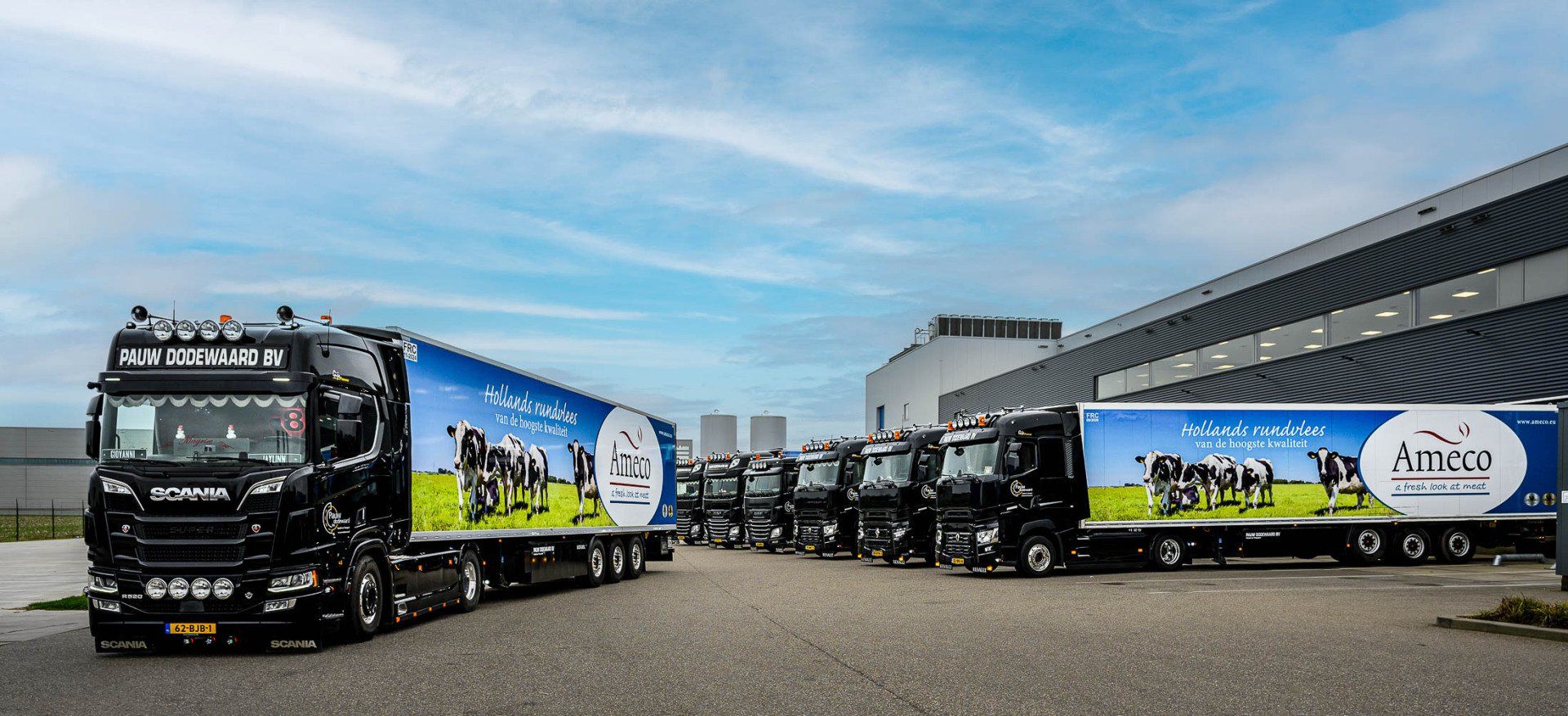 Een rij vrachtwagens geparkeerd voor een gebouw.