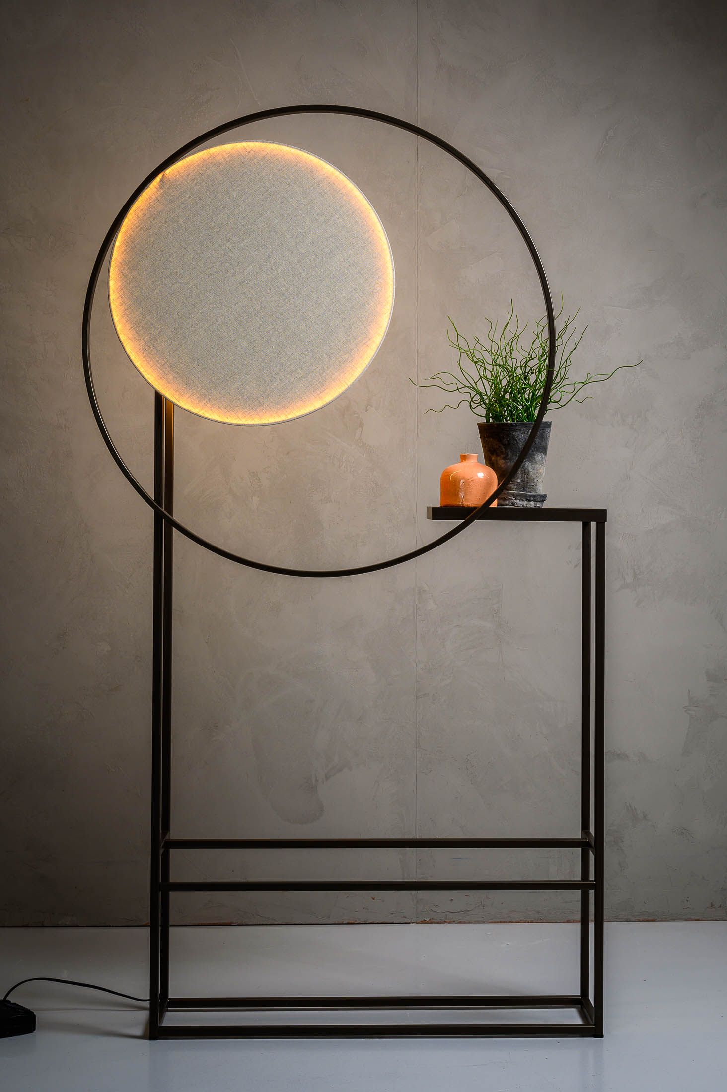 Er staat een lamp op een tafel naast een plant.