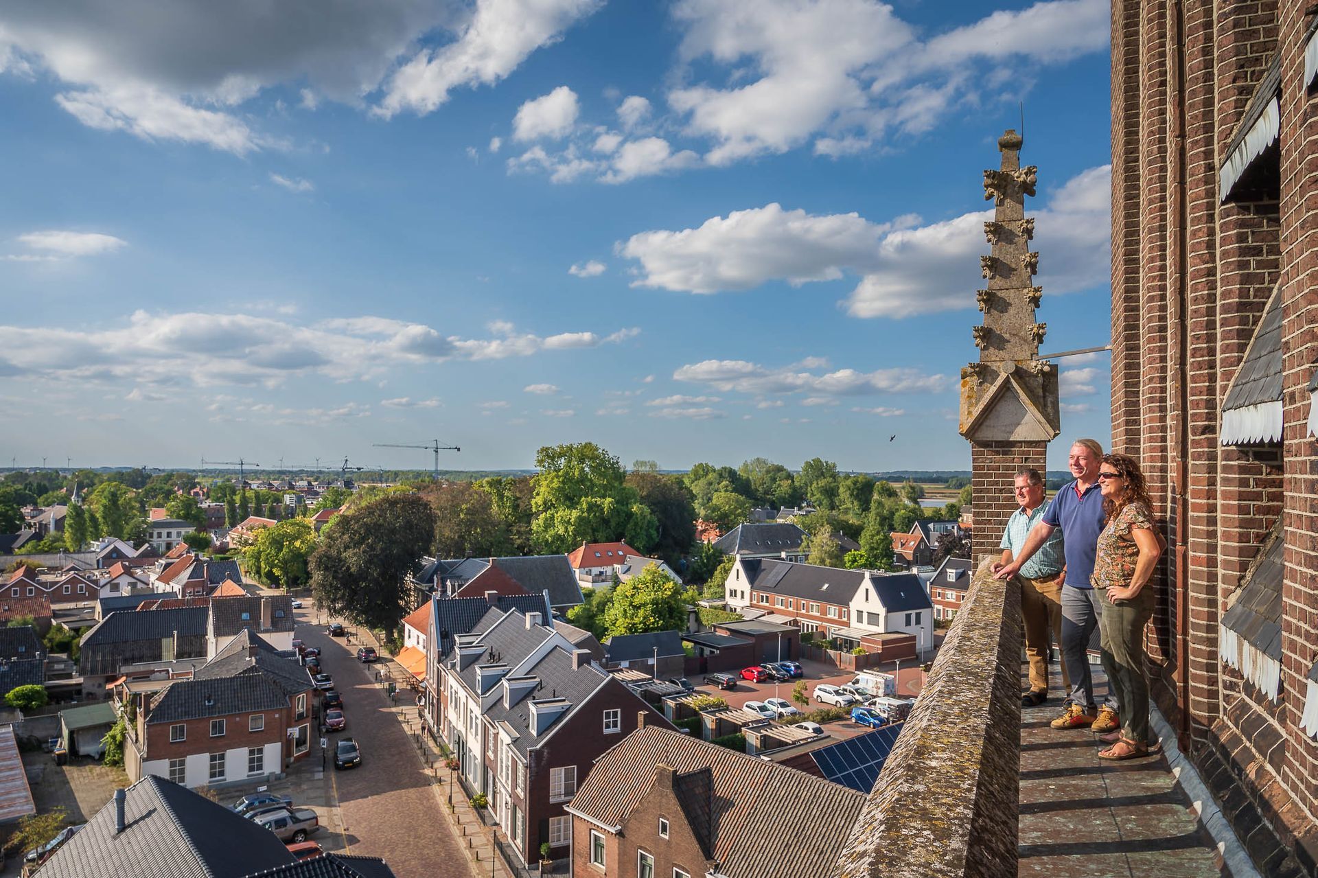 Een groep mensen die bovenop een bakstenen gebouw staan en uitkijken over een stad.