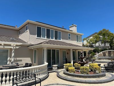Two-story house with a fountain, patio, and clear blue sky.