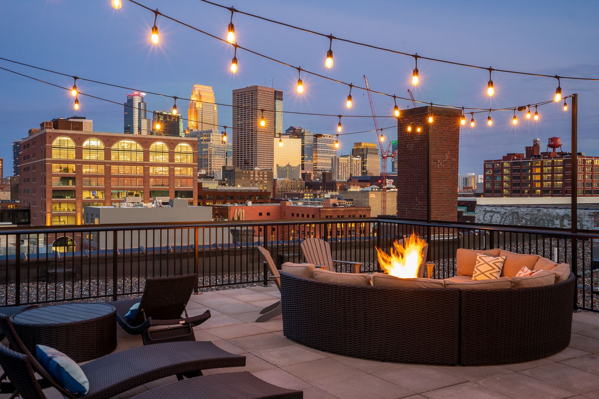 An aerial view of a rooftop terrace featuring a central lawn, lounge seating, a dining area, and a round table.
