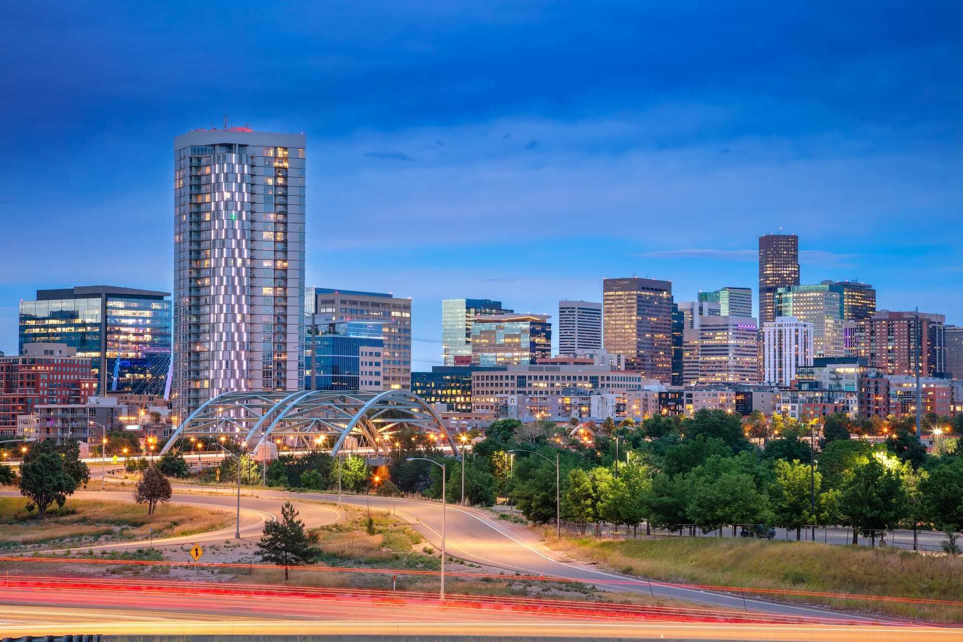 City skyline at dusk with modern high-rises and a lit roadway in the foreground