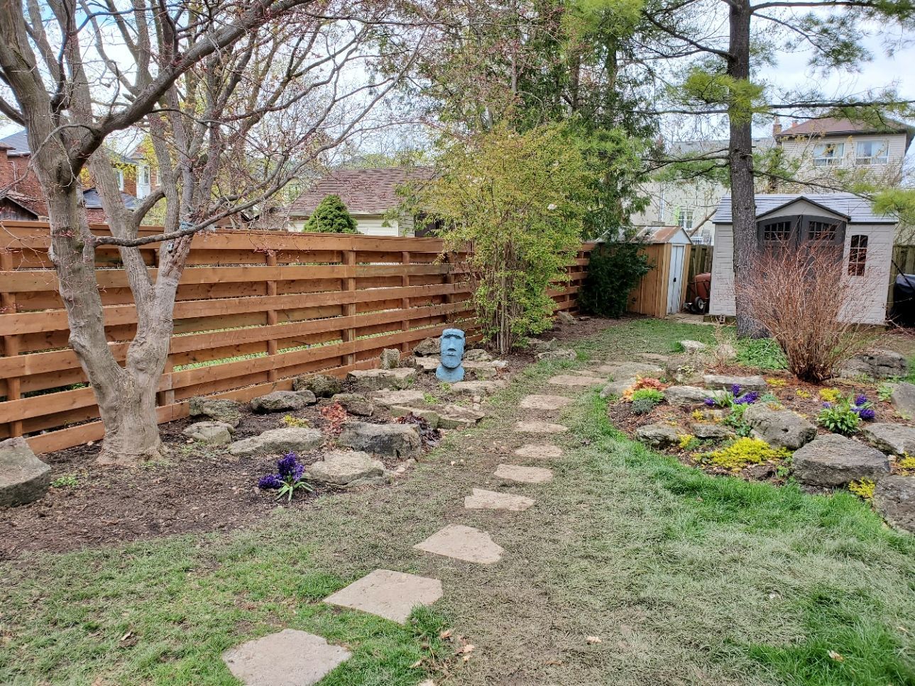 a backyard with a wooden fence and a stone path .