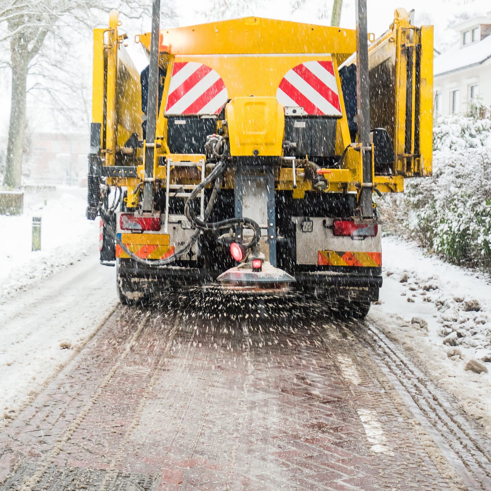 a yellow truck is driving down a snowy road