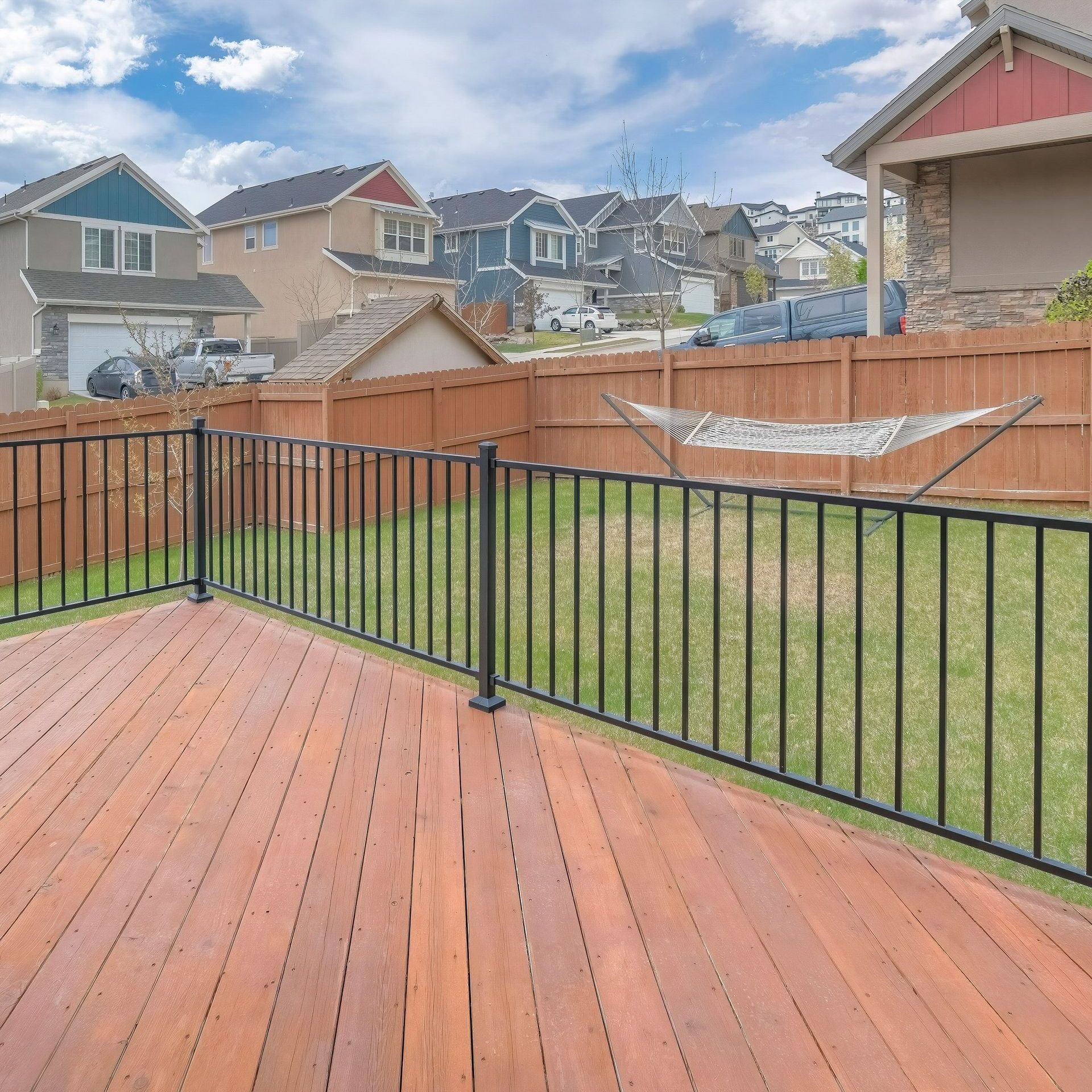 a wooden deck with a fence and a hammock in the backyard