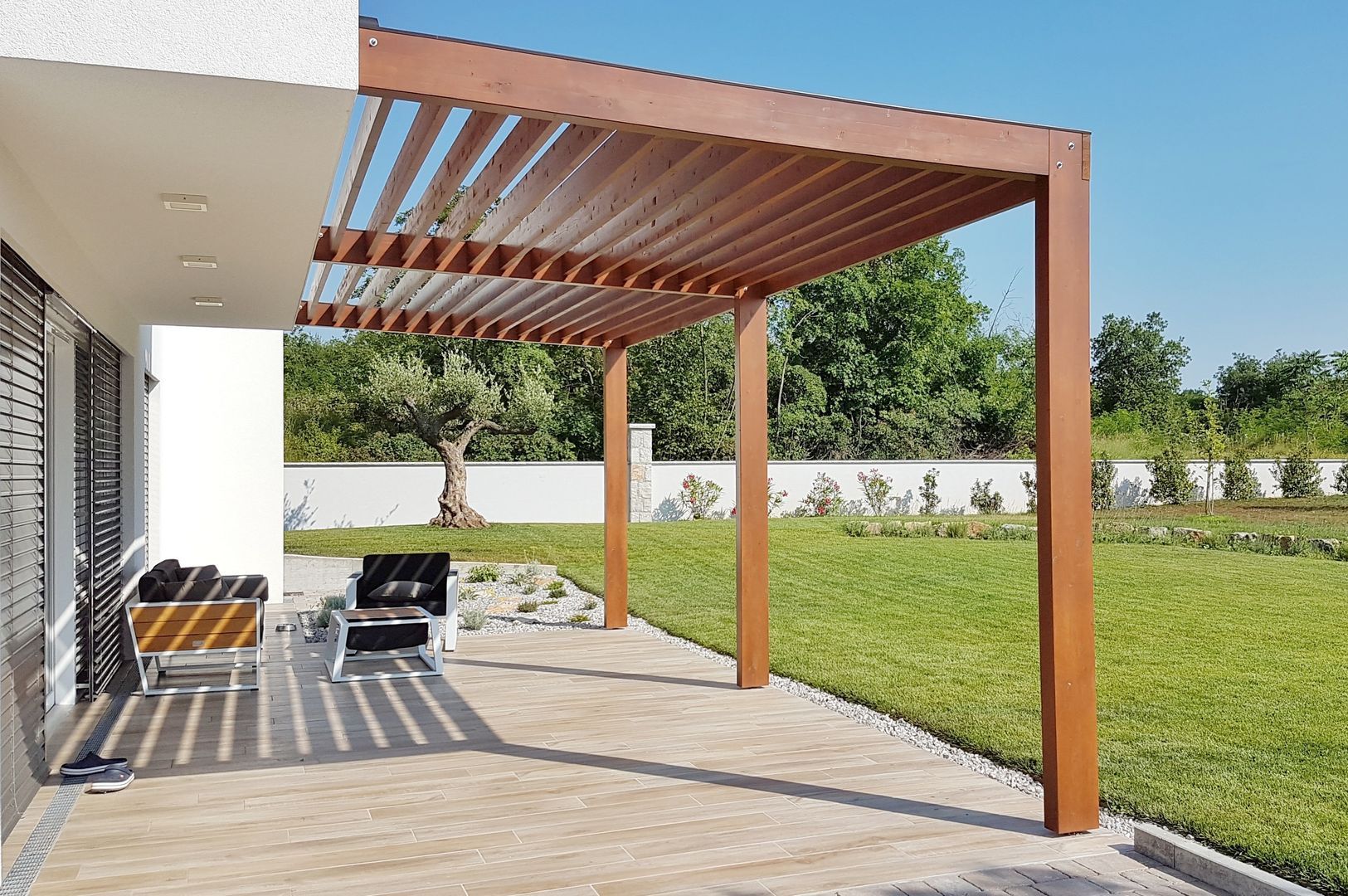 A wooden pergola is sitting on top of a patio next to a house.