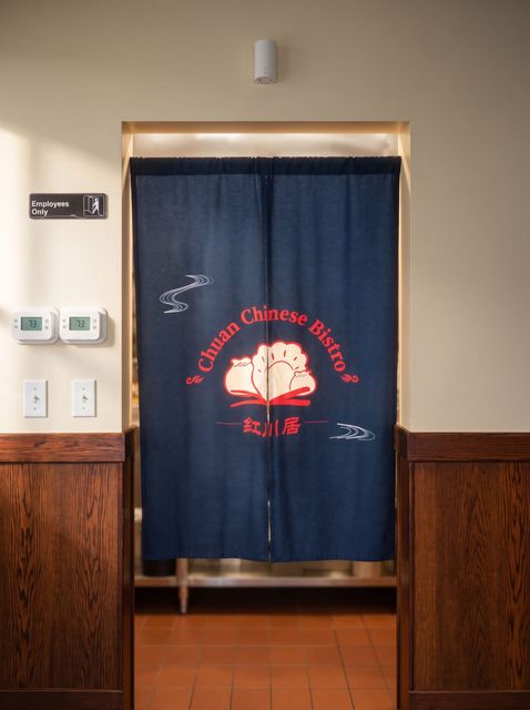 Blue curtain with a red-and-white Chinese restaurant logo in a doorway inside a wood-paneled interior