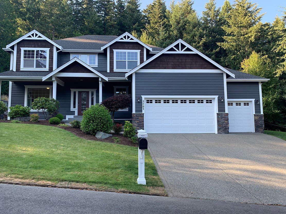 Dark gray two-story home with fresh exterior paint, white trim, and landscaped yard.