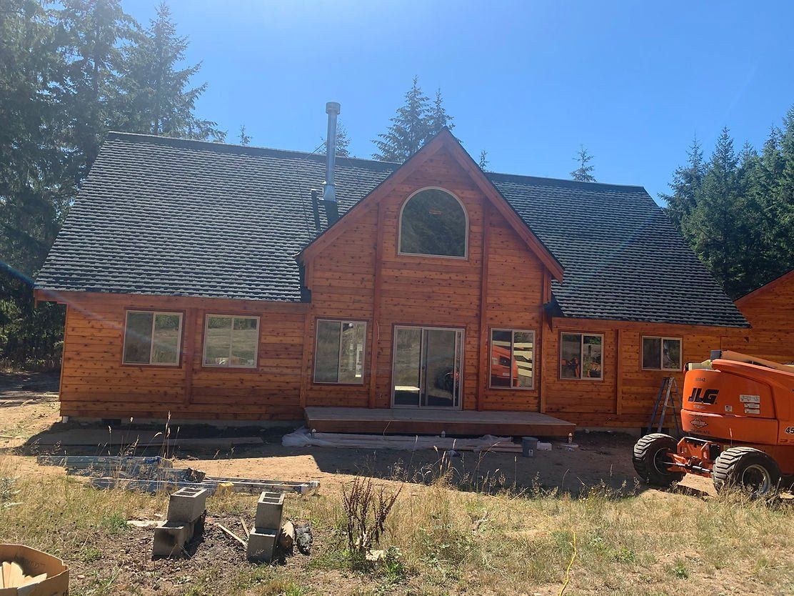 Rustic wood home with newly stained exterior siding and large front windows.