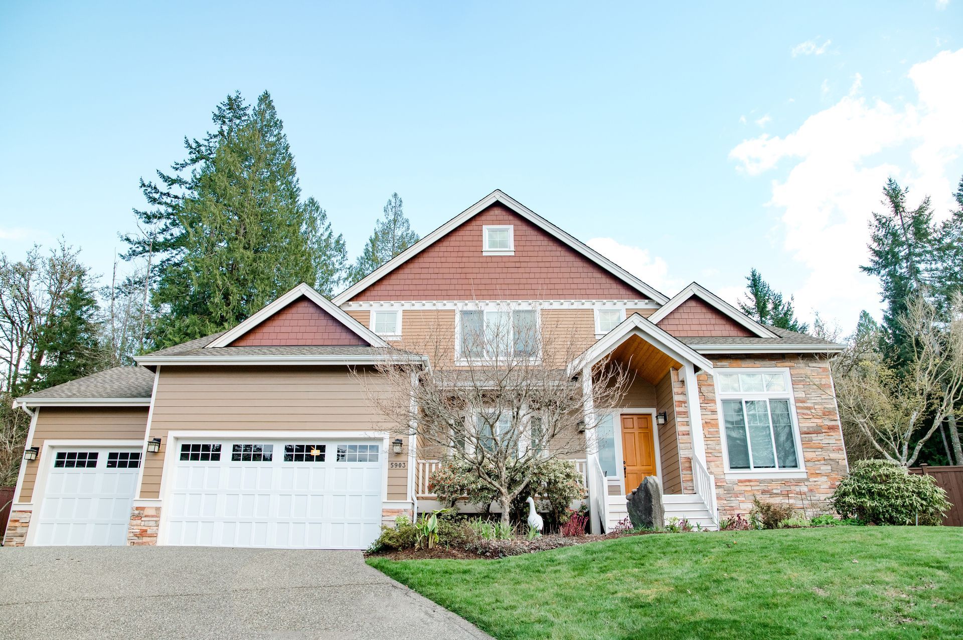A large house with a large garage and a lush green lawn.