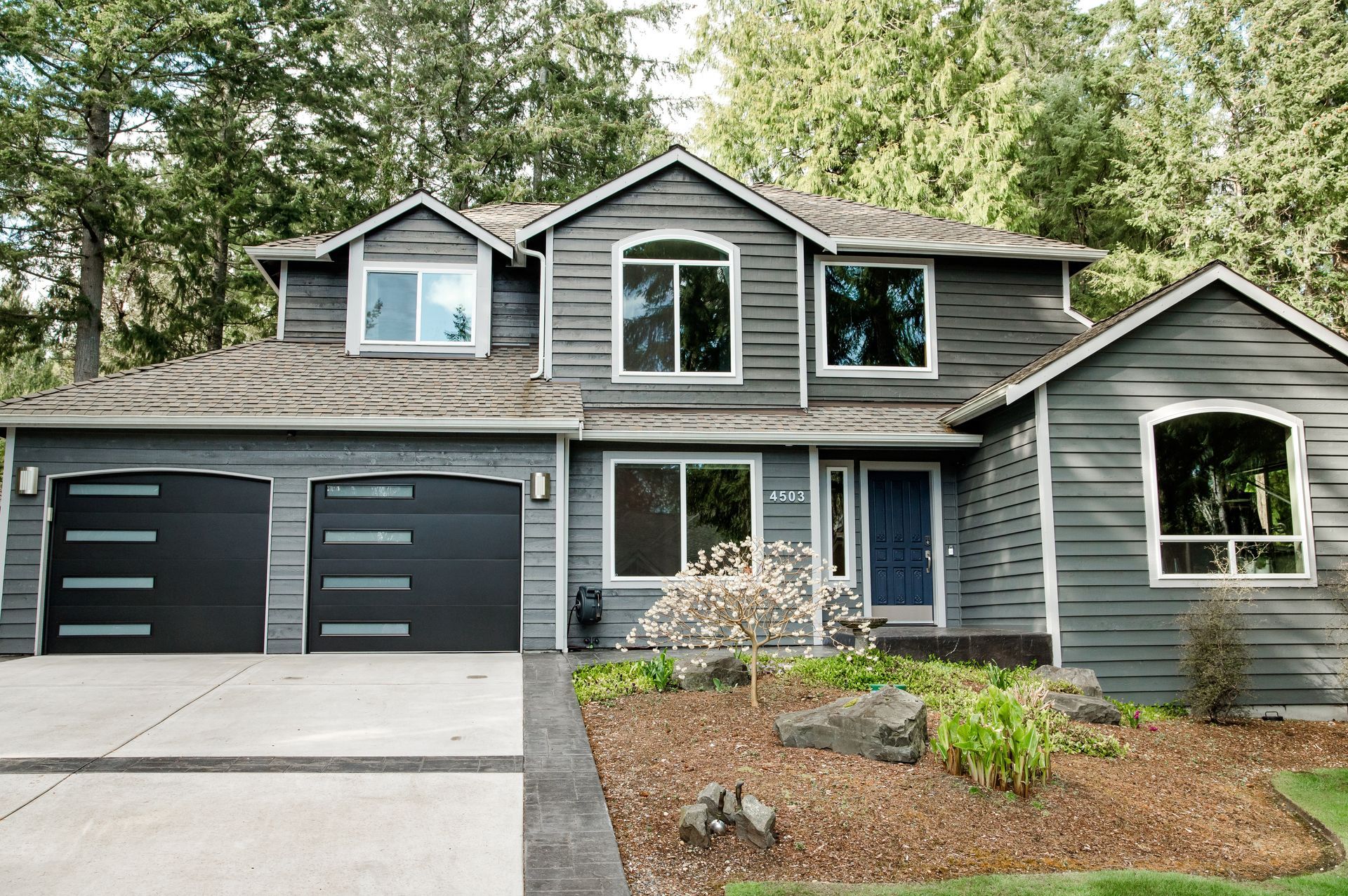A large gray house with two black garage doors