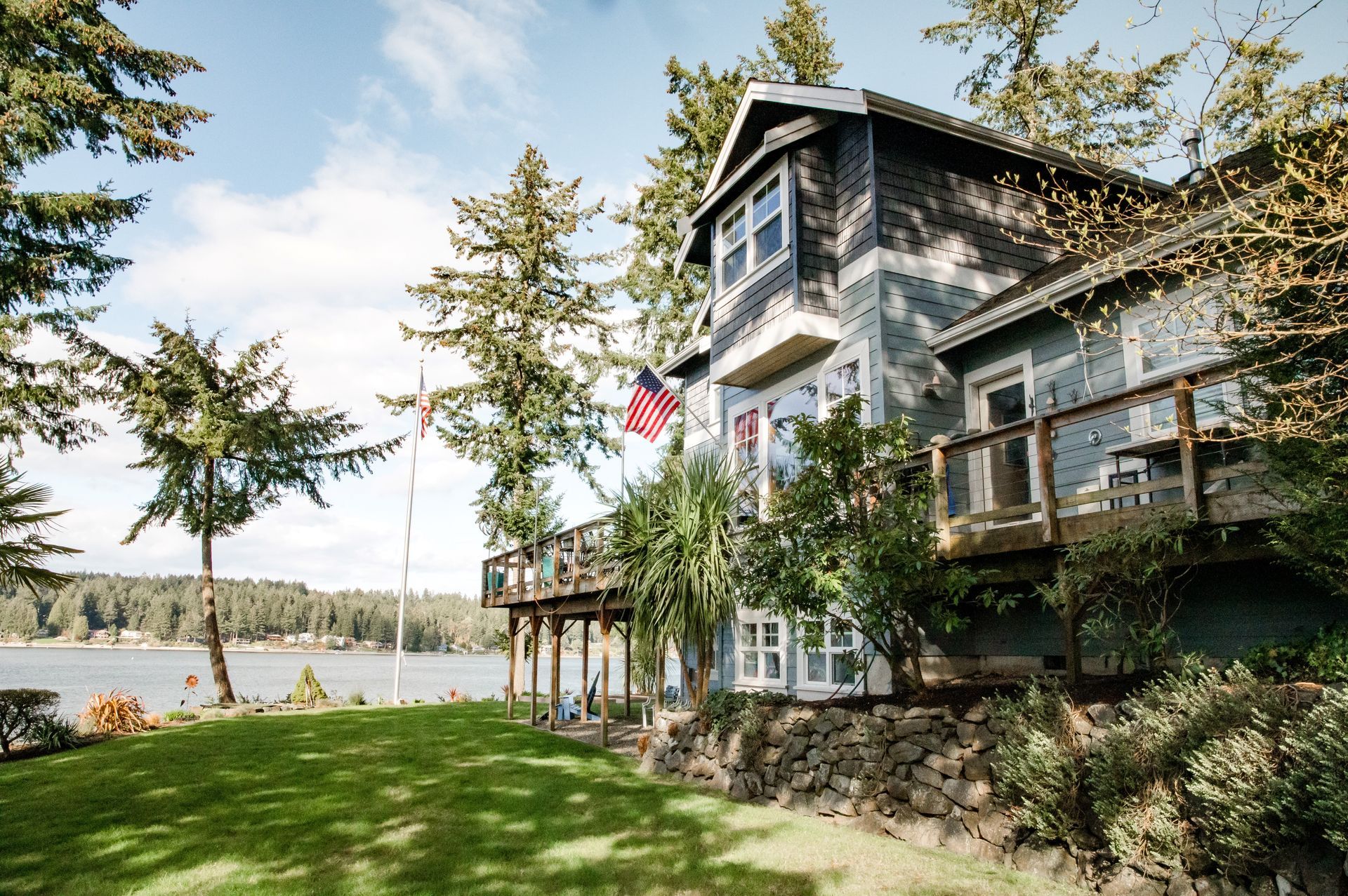 A large house sits on a hill overlooking a lake