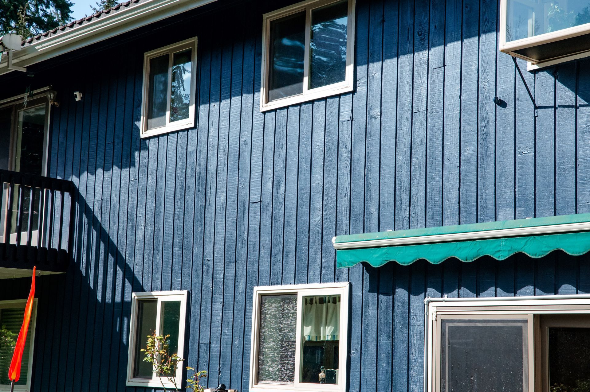 A blue house with white windows and a green awning