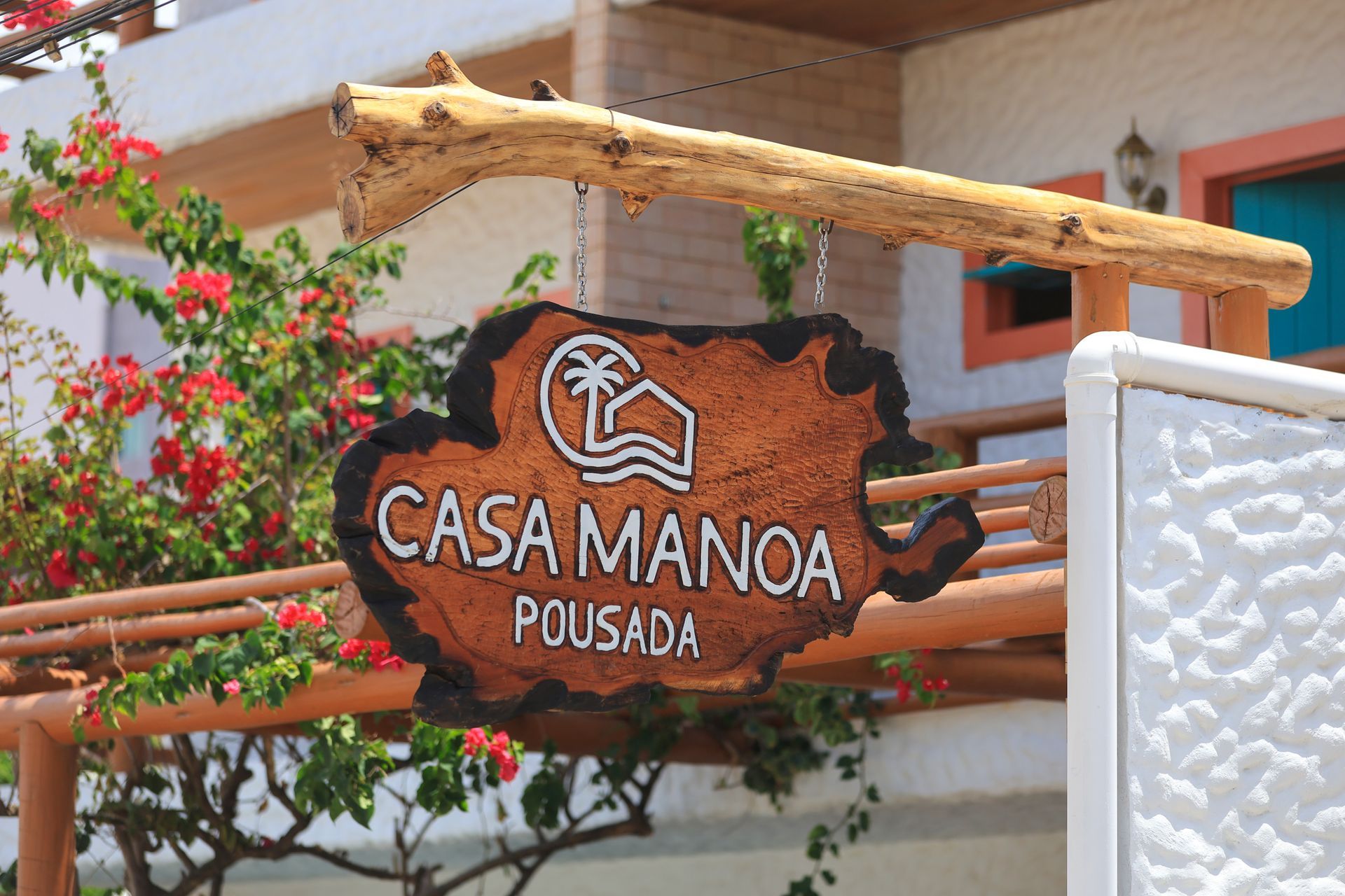 Uma placa de madeira que diz casa manoa pousada