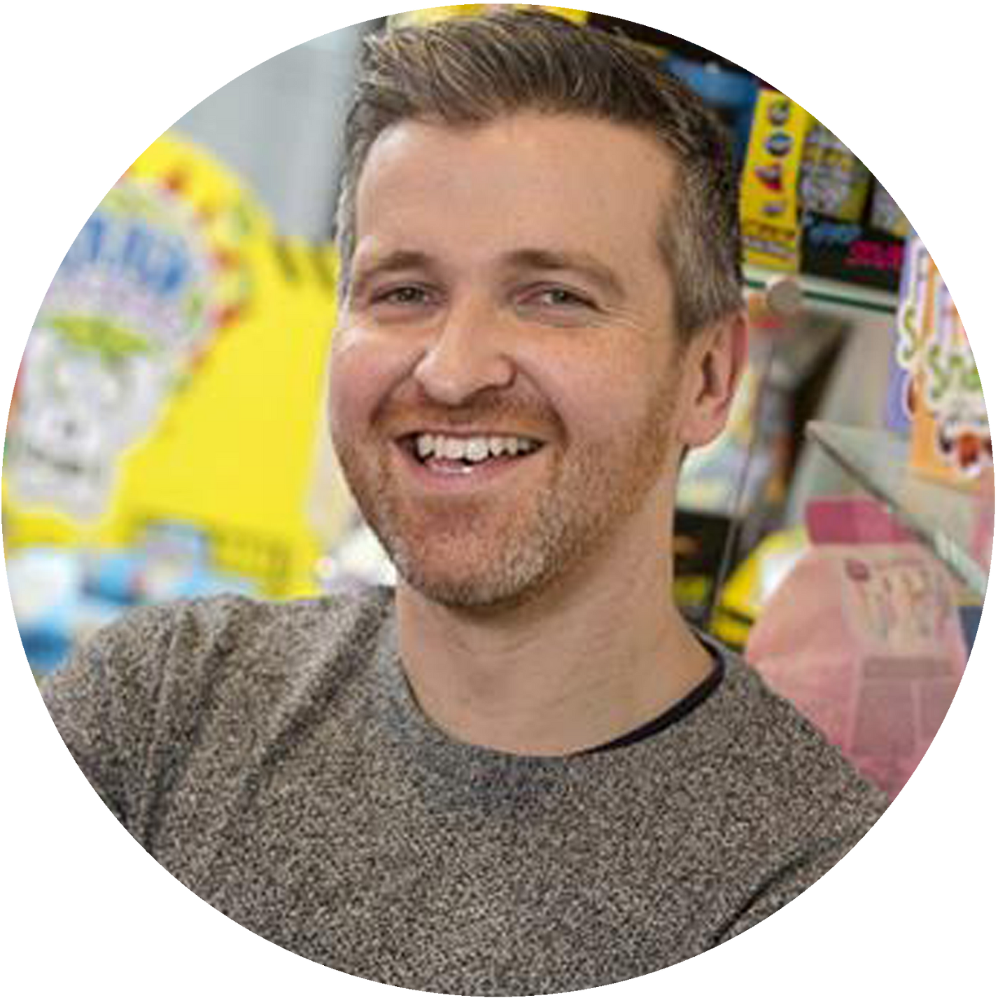 Smiling man in a gray sweater in a brightly colored shop interior
