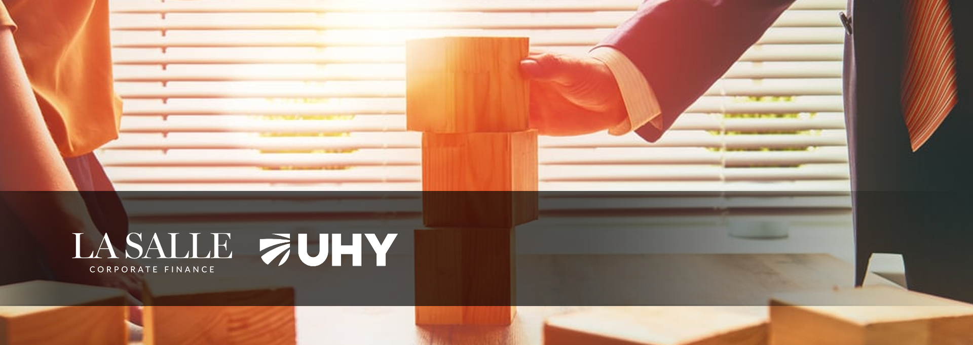 Orange shirt draped over a chair in a sunlit room with blinds and a banner reading “UHY”