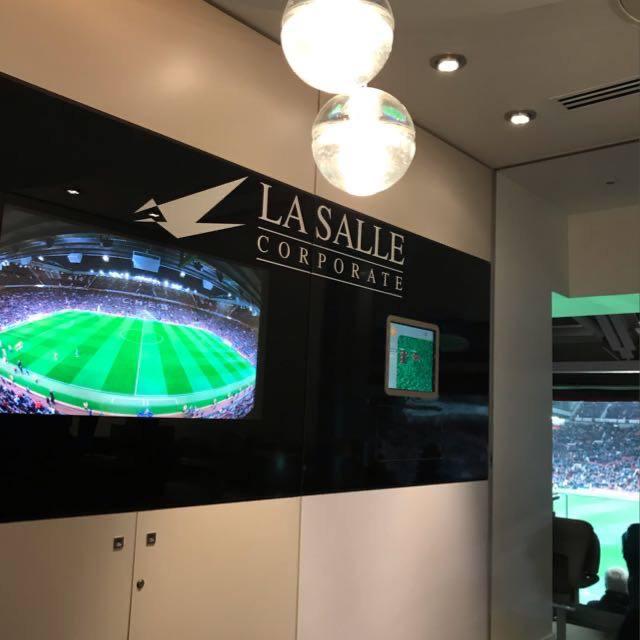 Corporate lobby with La Salle logo and wall-mounted TV showing a soccer stadium
