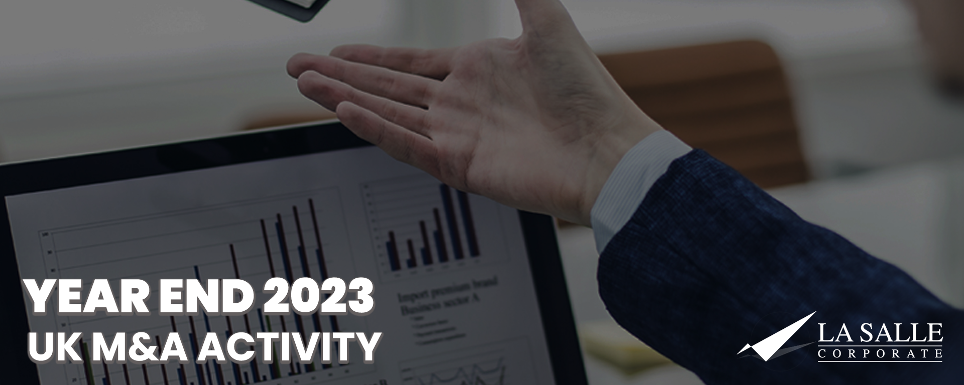 Hand holding a printed chart titled “YEAR END 2023 UK M&A ACTIVITY” with LaSalle logo
