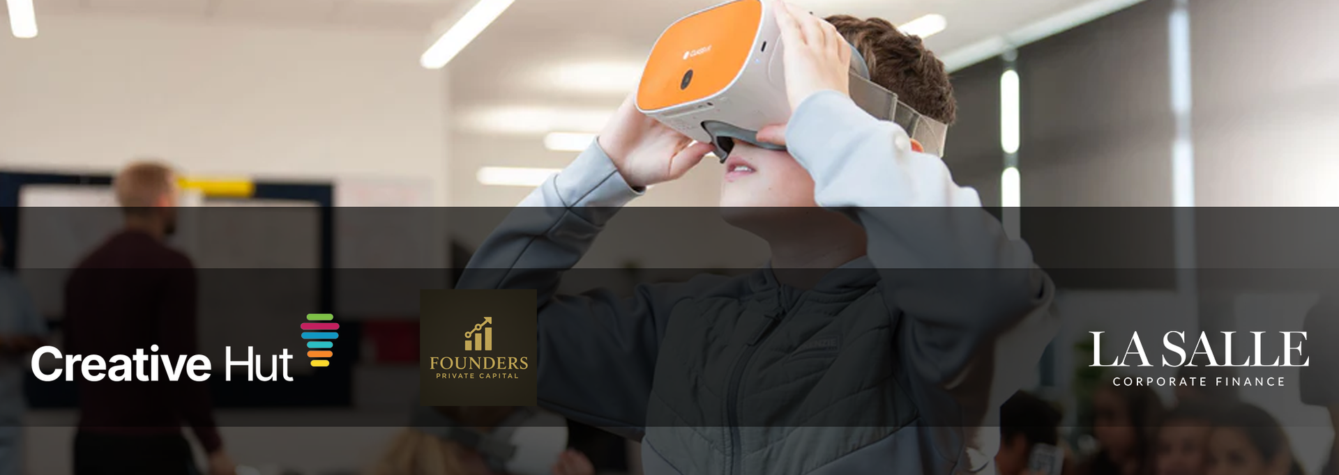 Person holding an orange VR headset in a classroom with “Creative Hut” and “La Salle” logos