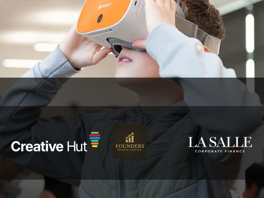 Person wearing an orange VR headset at a Creative Hut event, with sponsor logos displayed below