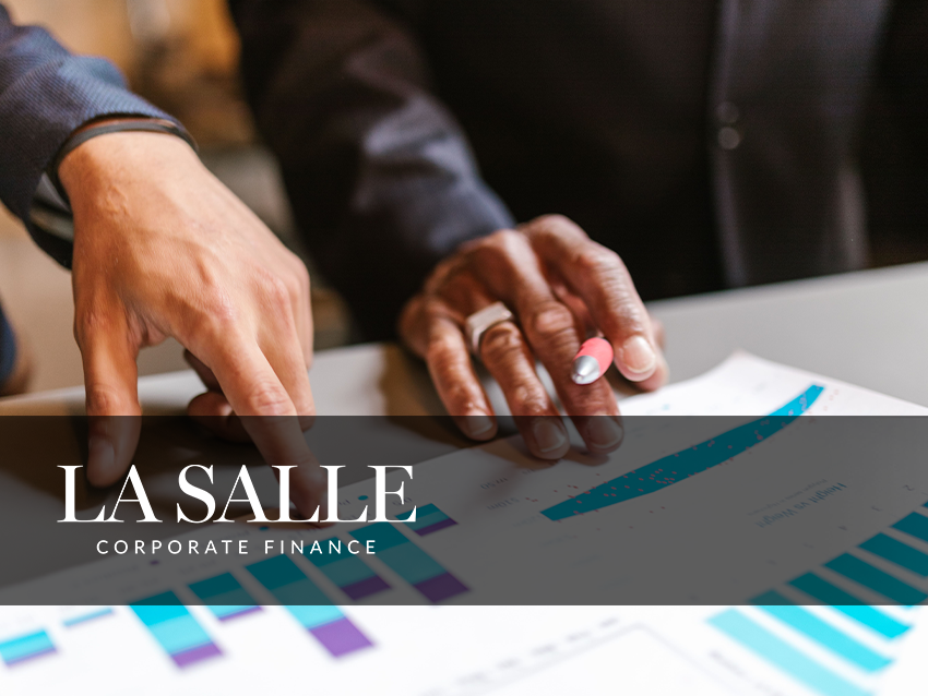 Hands pointing at financial charts on a desk with a “La Salle Corporate Finance” banner.
