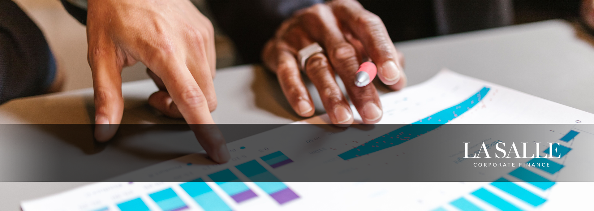 Hands pointing to a bar chart with a rising blue line on a desk with documents.