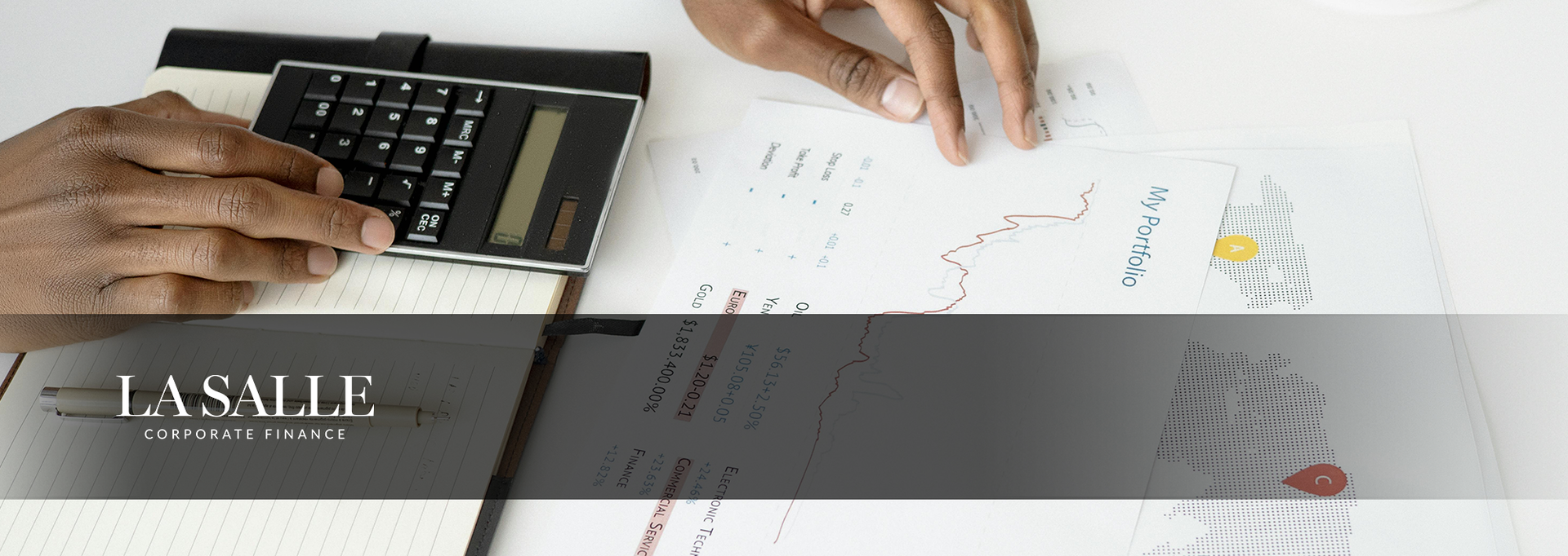 Hands using a calculator and pointing at printed charts on a desk in a business meeting