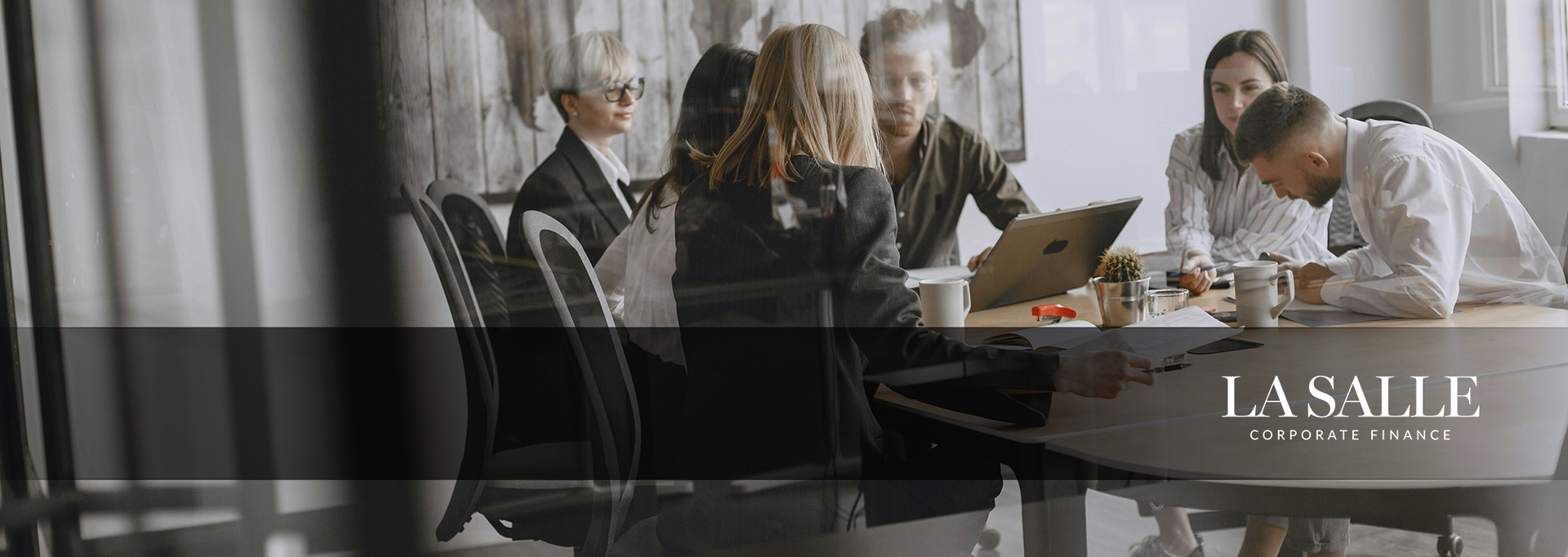 People meeting around a table in a modern office, with a laptop and notebooks in view