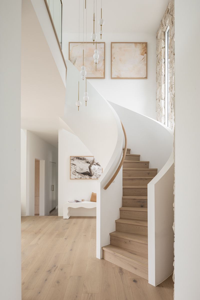 Elegant curved staircase with light wood steps, white walls, and artwork — SDC Building Design In Wollongong, NSW