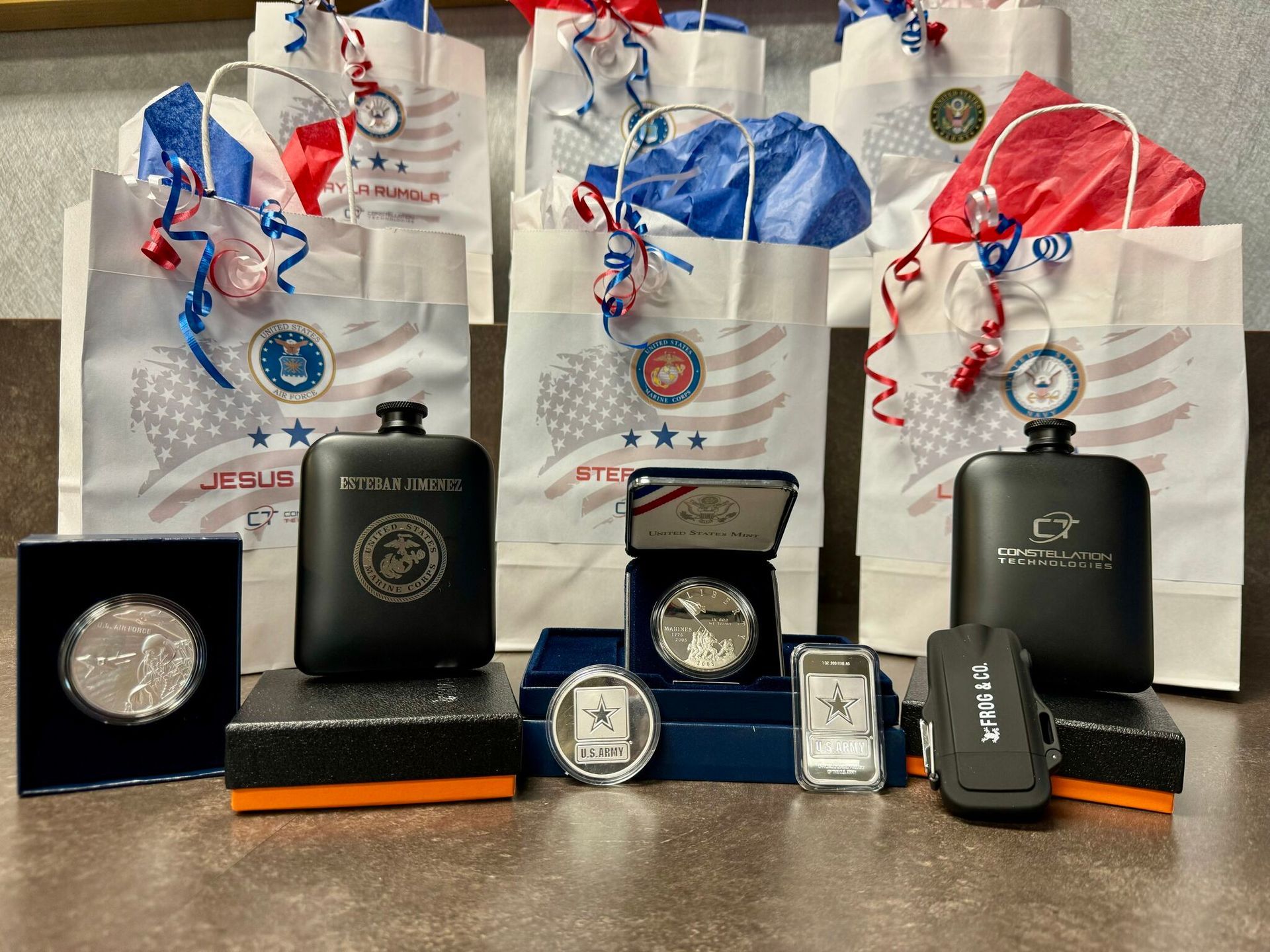 A display of patriotic gift bags, metal flasks, and commemorative coins and bars.