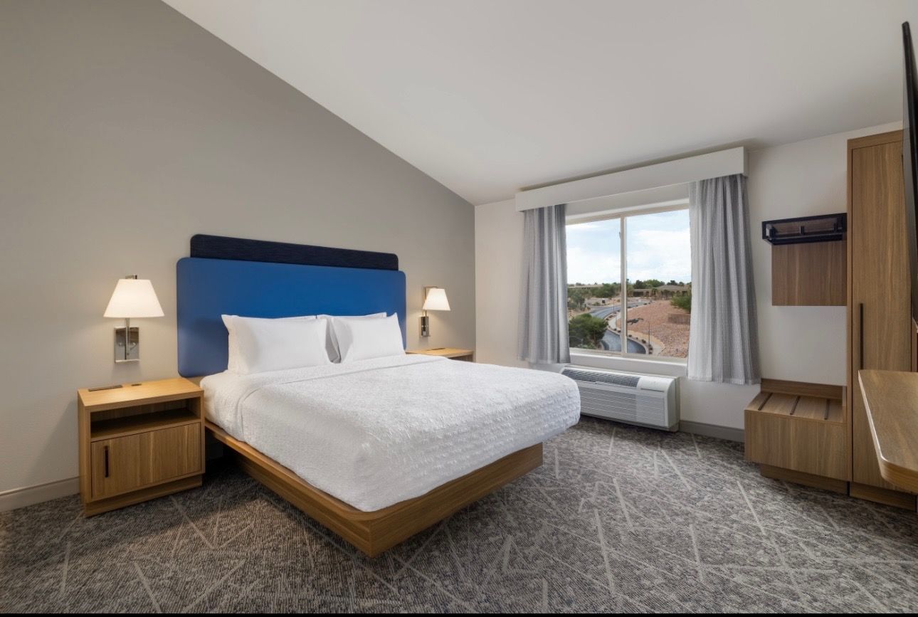 Hotel room with a bed, nightstands, and a window with a view.