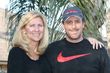 Woman and man smiling, standing outside near palm fronds. Man has arm around woman.