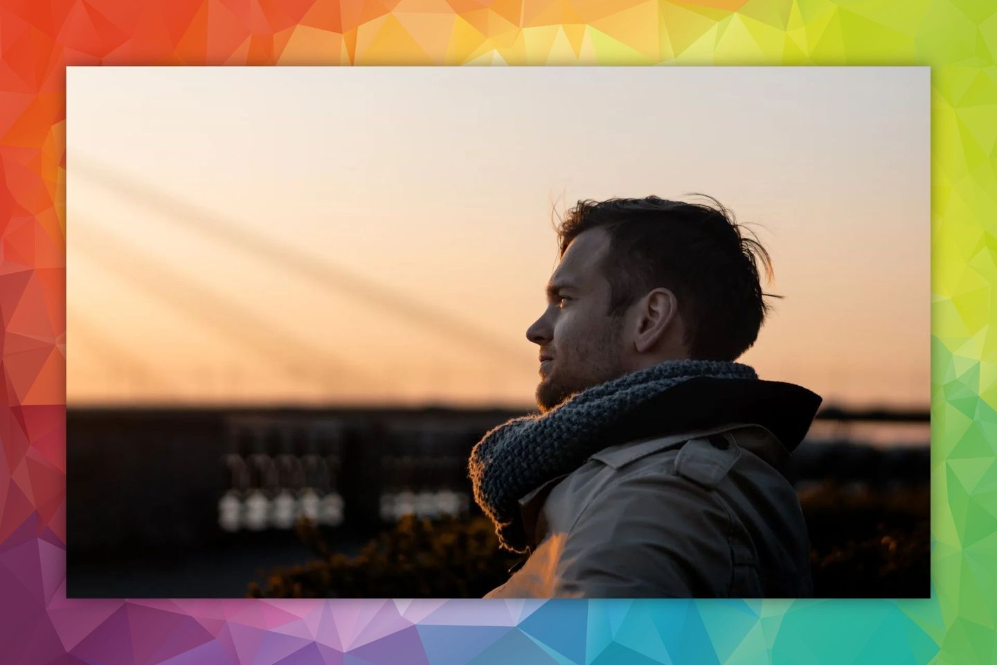 Man in profile looking at a sunset, wearing a scarf and coat, with a blurred background.