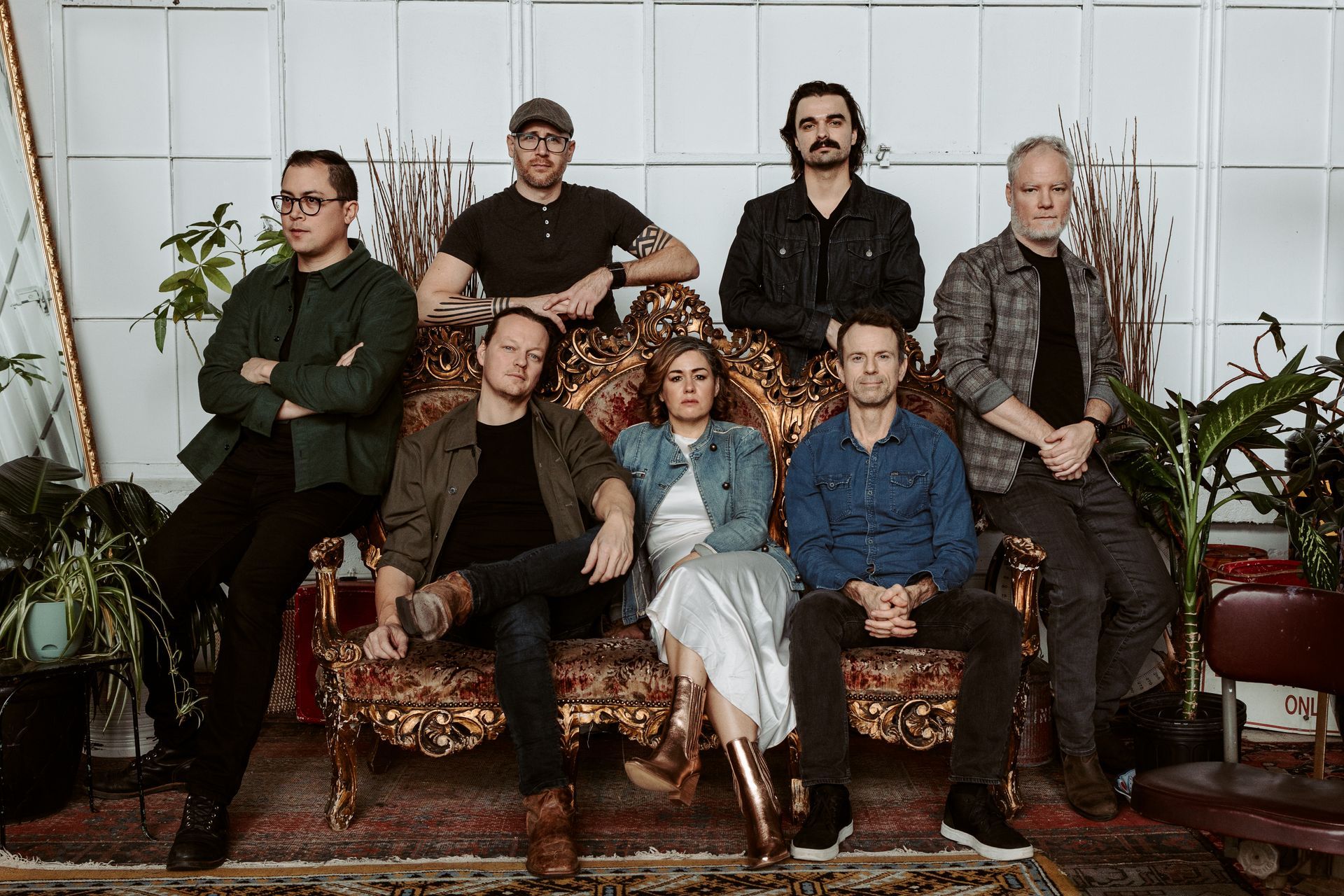 A group of people are posing for a picture while sitting on a couch.