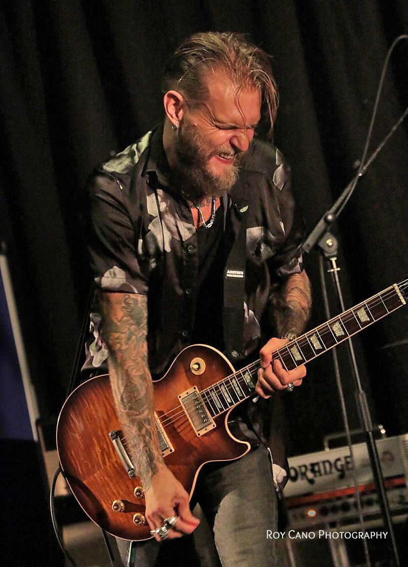 Ben Poole with contorted face playing guitar on stage.