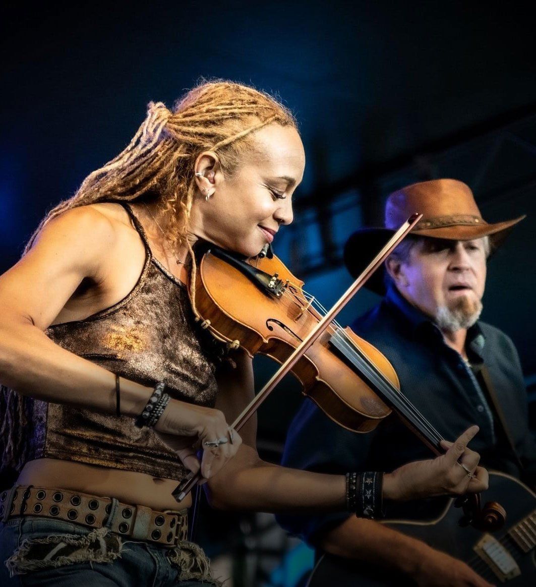 A woman playing a violin next to a man playing a guitar