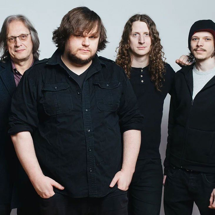 A group of men standing next to each other with their hands in their pockets