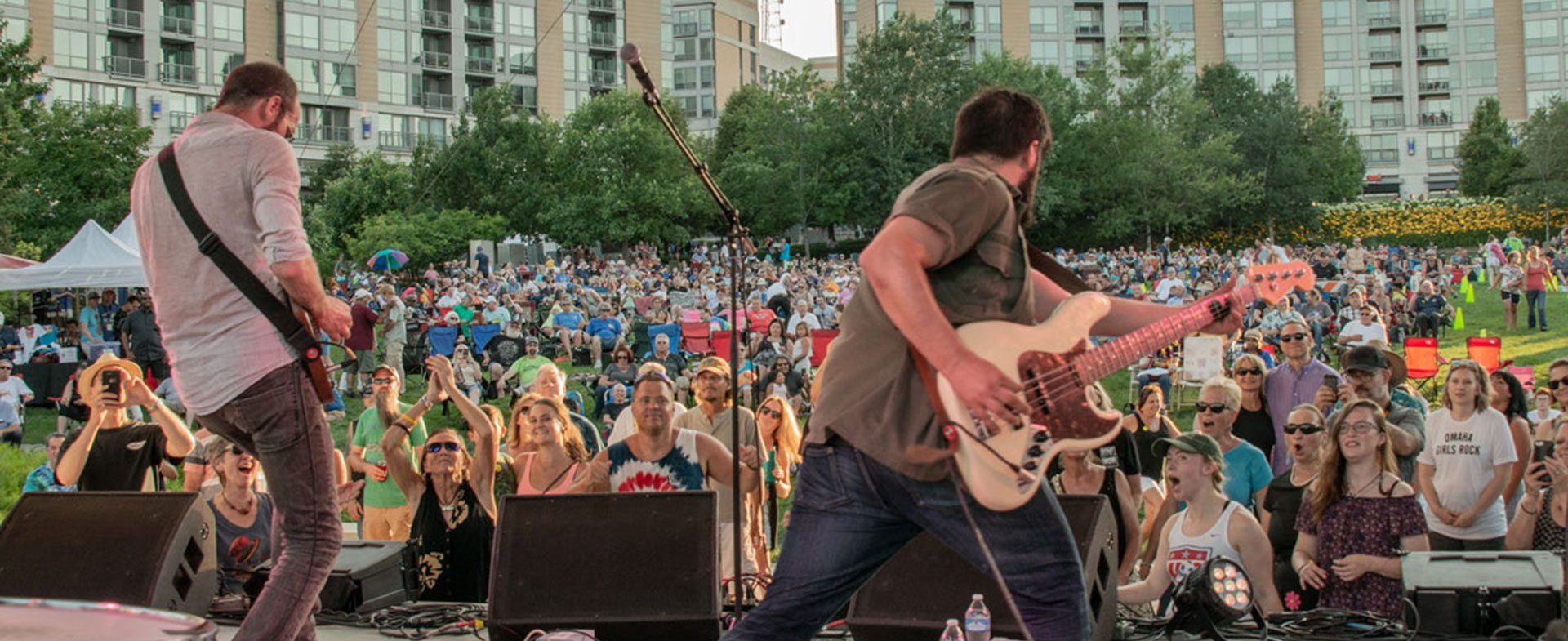 Two men are playing guitars on a stage in front of a crowd.