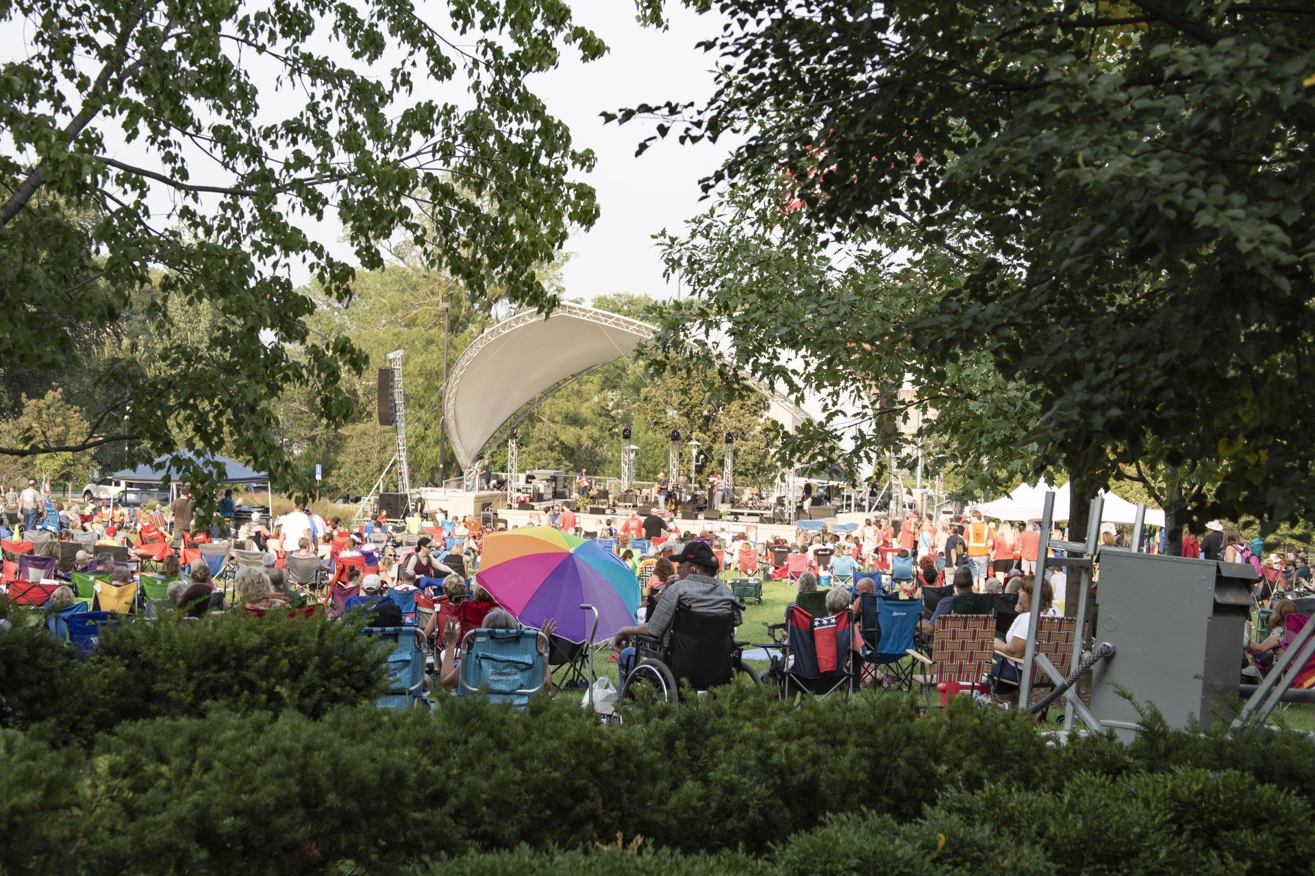 A crowd of people are sitting under an umbrella in a park