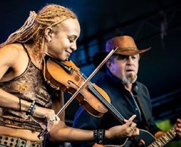 A woman playing a violin next to a man playing a guitar