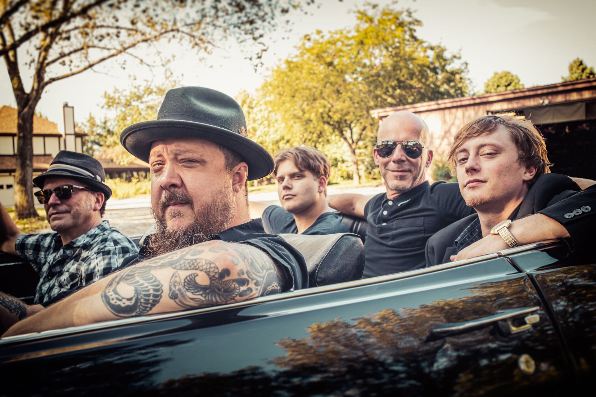 A group of men are sitting in a convertible car.