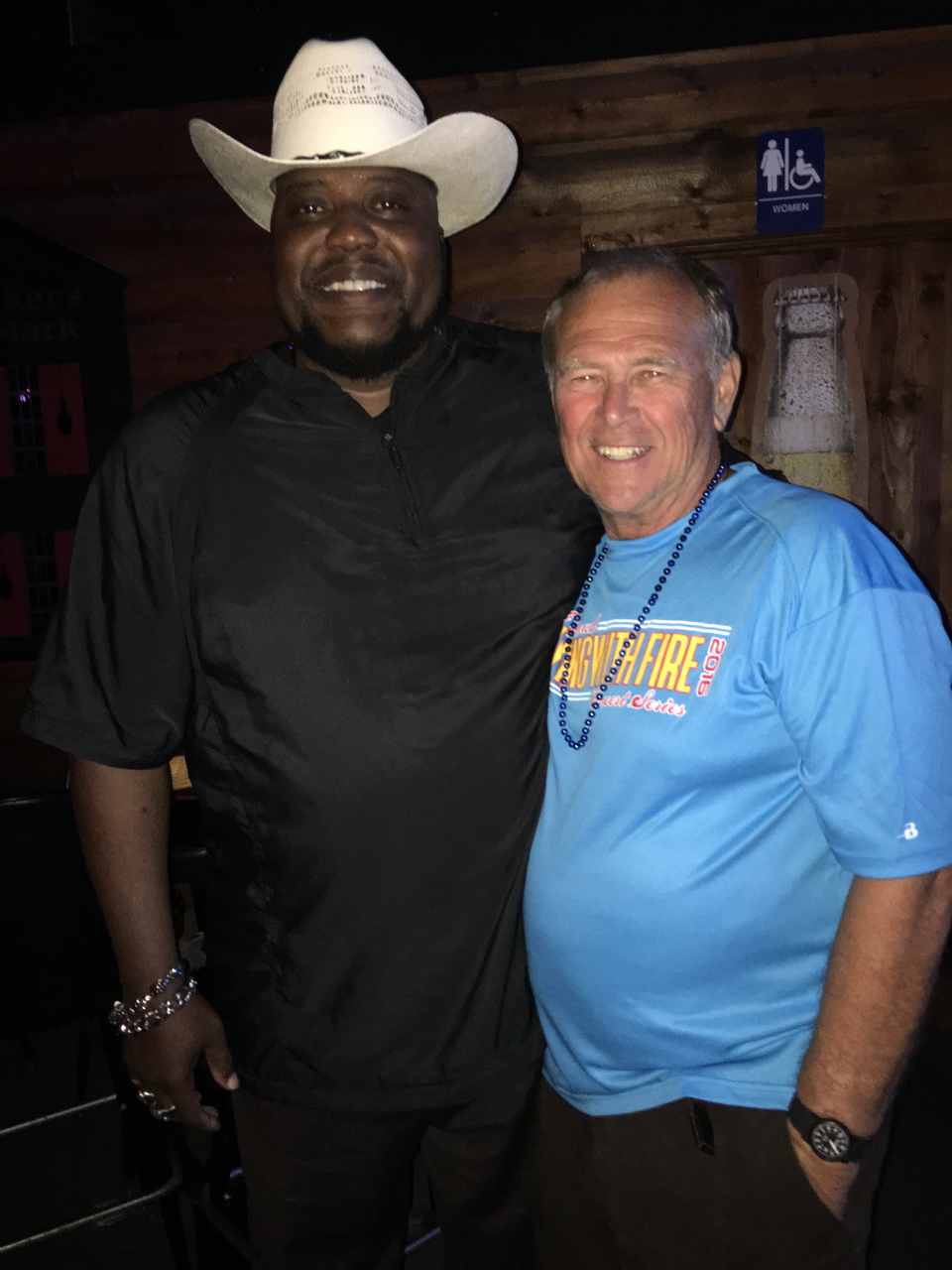A man wearing a cowboy hat is posing for a picture with another man