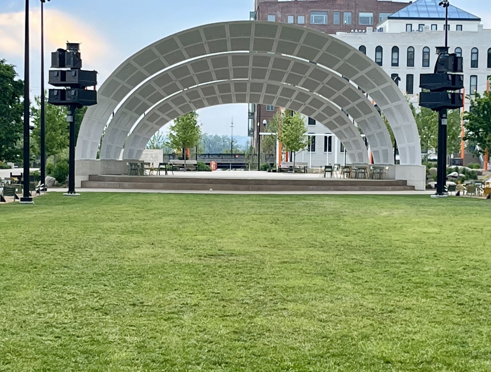 An empty stage in a park with a building in the background