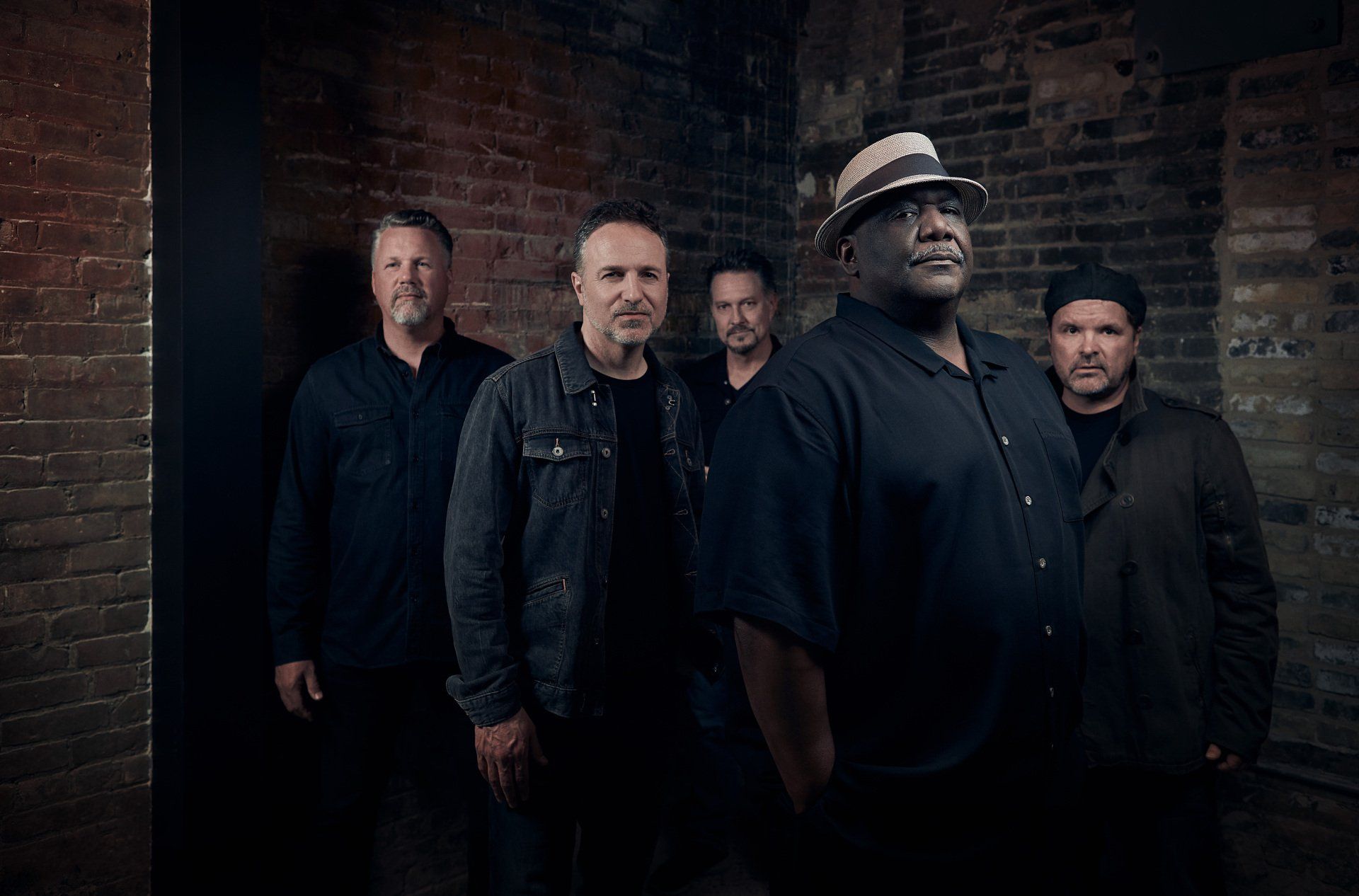 A group of men are standing next to each other in front of a brick wall.
